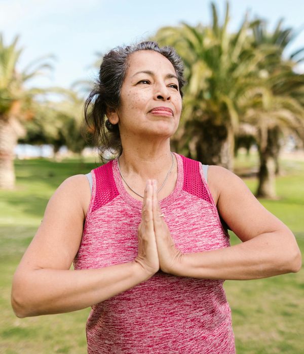 Smiling person stretching outdoors in a park.